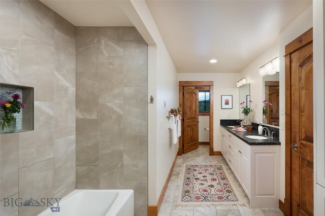 bathroom with double vanity, a bathing tub, baseboards, and a sink