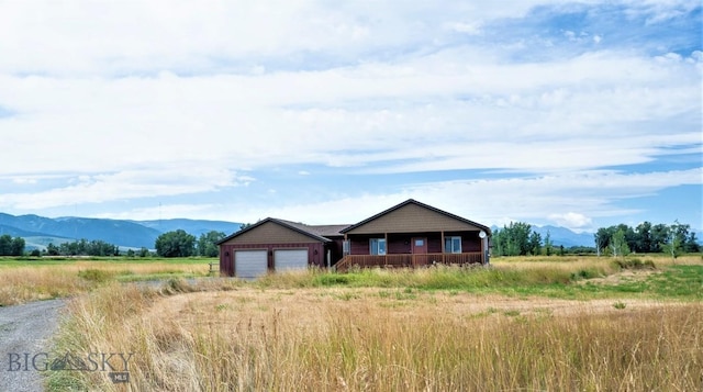 view of front of home with a rural view, an attached garage, and a mountain view