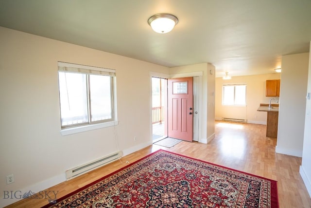 foyer entrance with a baseboard radiator, baseboards, and light wood-style flooring