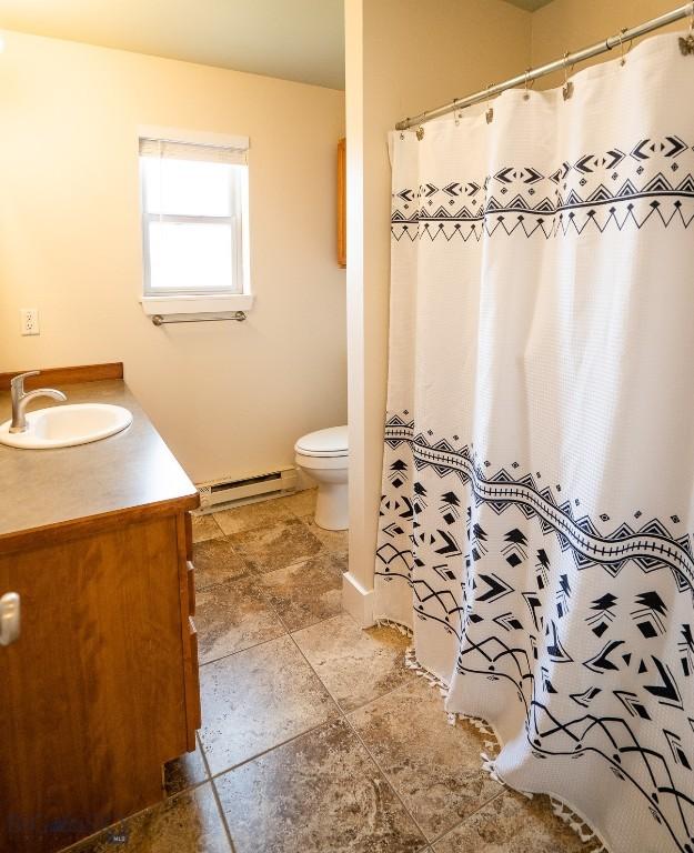 bathroom featuring toilet, baseboard heating, vanity, and a shower with curtain