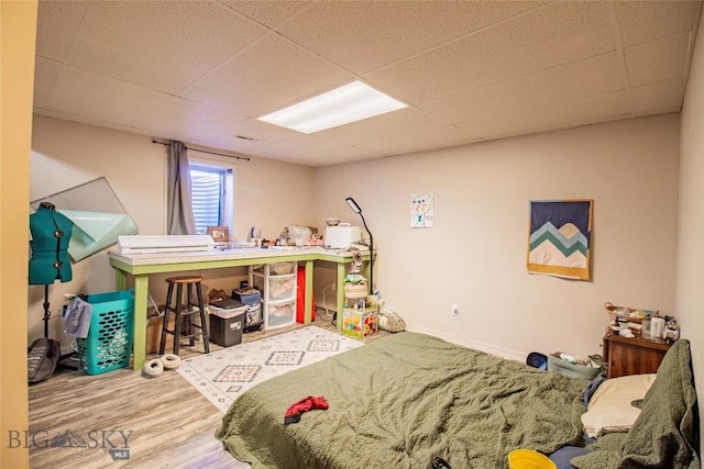 bedroom with hardwood / wood-style floors and a paneled ceiling