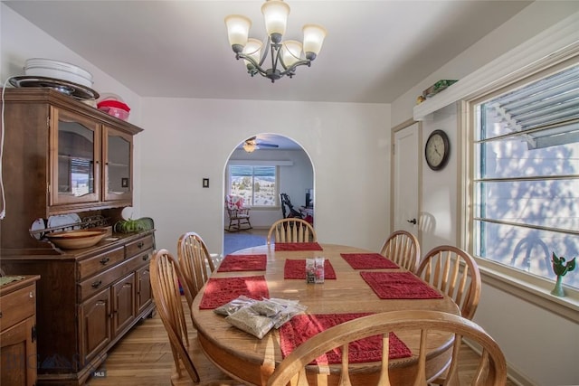 dining area with hardwood / wood-style floors and ceiling fan with notable chandelier