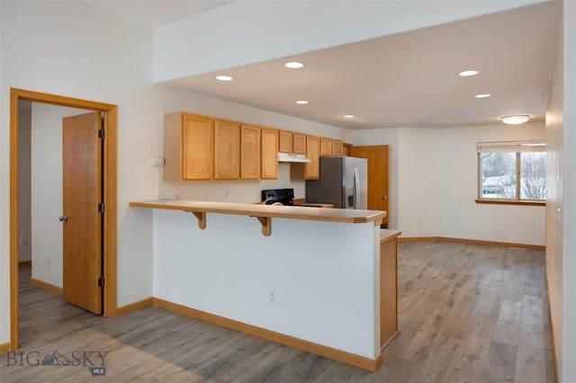 1121 Buckrake Ave, Bozeman, MT 59718 - kitchen with stainless steel refrigerator with ice dispenser, under cabinet range hood, light wood-style flooring, a breakfast bar area, and a peninsula