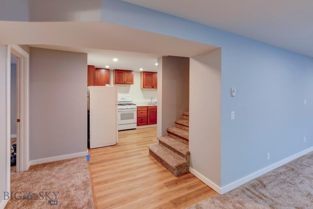 kitchen featuring sink, white appliances, and light wood-type flooring