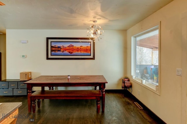 dining room with dark hardwood / wood-style flooring and a chandelier