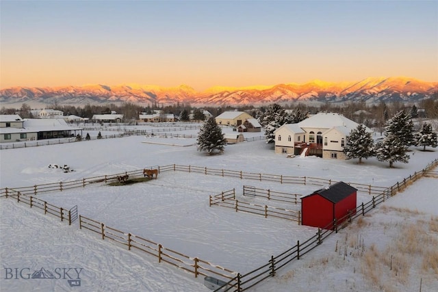 snowy aerial view featuring a mountain view and a rural view