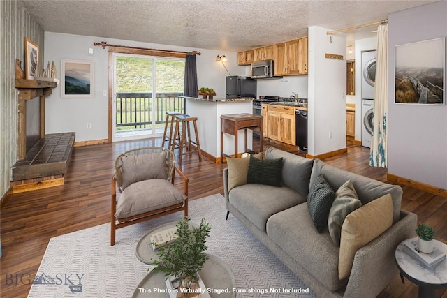 living room featuring stacked washer and dryer, sink, dark hardwood / wood-style floors, and a textured ceiling