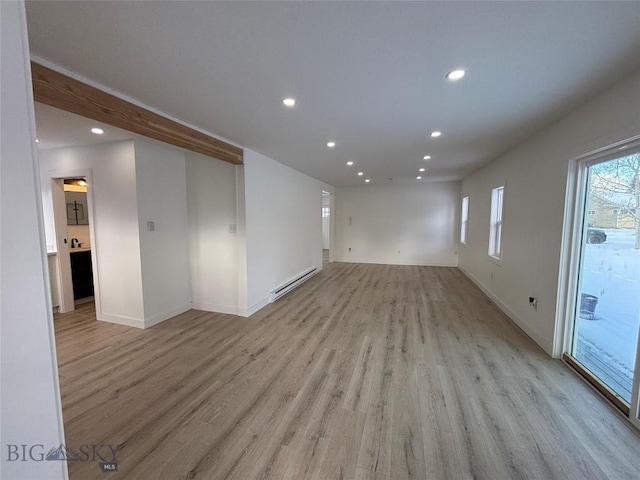 empty room with light hardwood / wood-style flooring and a baseboard heating unit