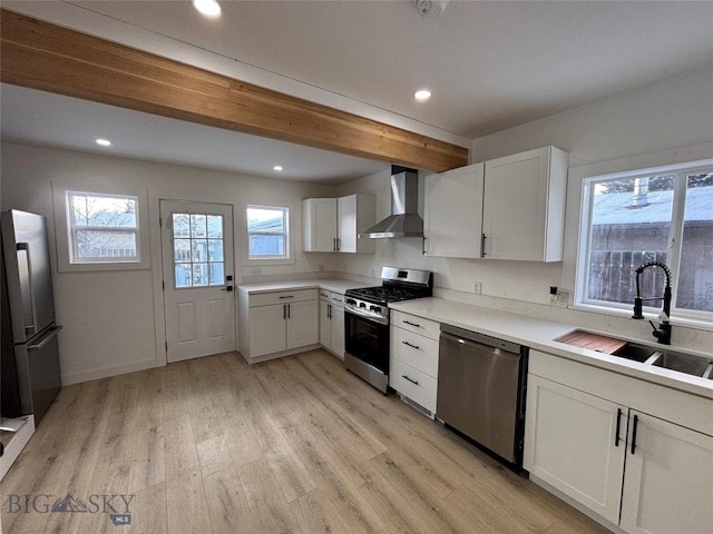 kitchen featuring sink, wall chimney exhaust hood, beamed ceiling, white cabinets, and appliances with stainless steel finishes