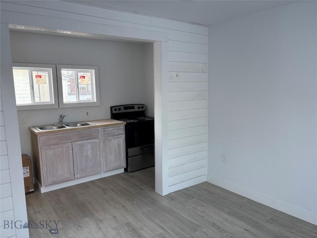 kitchen featuring light brown cabinetry, electric range, light hardwood / wood-style flooring, and sink