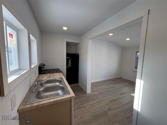 kitchen with light hardwood / wood-style floors, black fridge, washer / clothes dryer, and sink