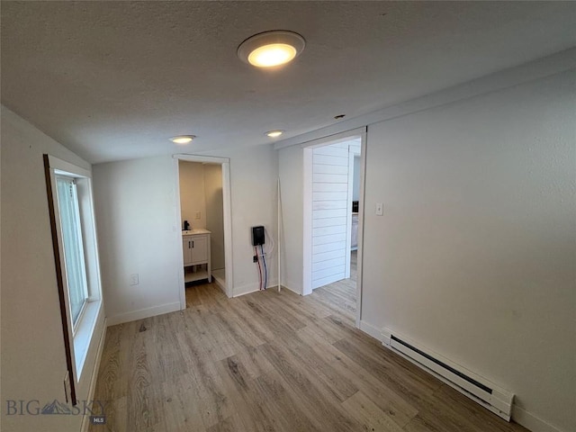 spare room with light wood-type flooring, vaulted ceiling, and a baseboard heating unit