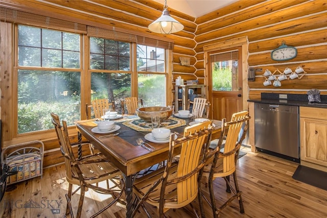 dining room with light hardwood / wood-style flooring, log walls, and a wealth of natural light