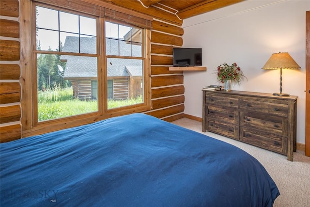 bedroom featuring multiple windows, log walls, beamed ceiling, and light colored carpet