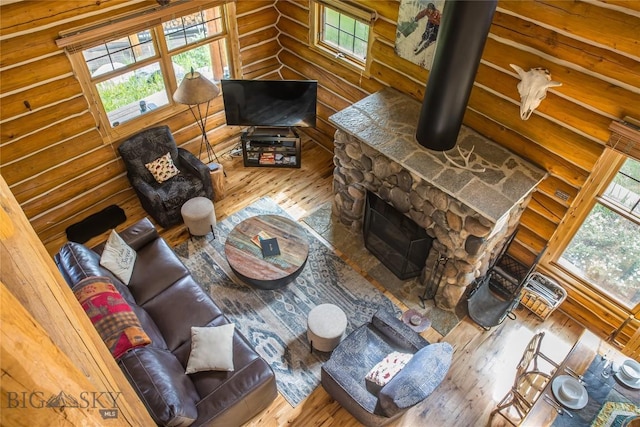 living room with hardwood / wood-style floors, a stone fireplace, and log walls