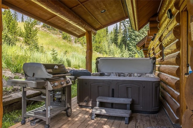 wooden deck featuring a hot tub and a grill