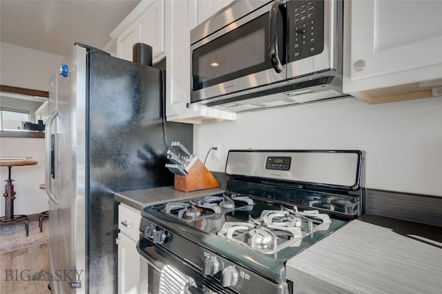 kitchen with light hardwood / wood-style floors, white cabinetry, and stainless steel appliances