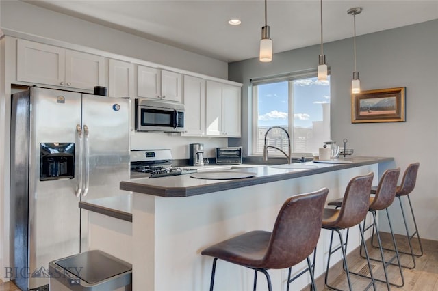 kitchen with white cabinets, kitchen peninsula, and appliances with stainless steel finishes