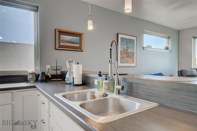 kitchen featuring white cabinets, hanging light fixtures, and sink