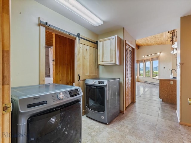 laundry room with sink, cabinets, a barn door, light tile patterned flooring, and washer and dryer