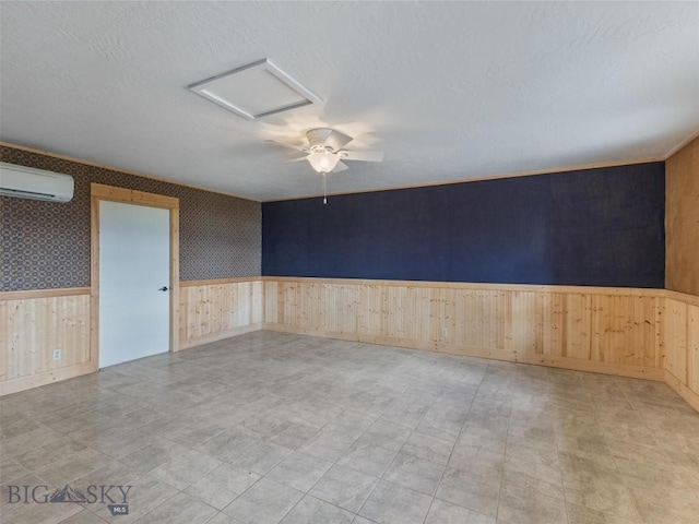 empty room featuring a wall unit AC, wood walls, ceiling fan, and a textured ceiling