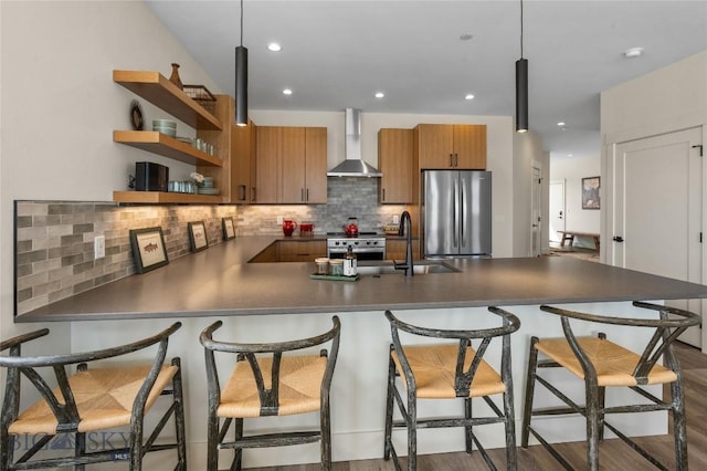 420 Sage Ave Unit B, Ennis, MT 59729 - kitchen featuring wall chimney range hood, dark countertops, a sink, brown cabinetry, and appliances with stainless steel finishes