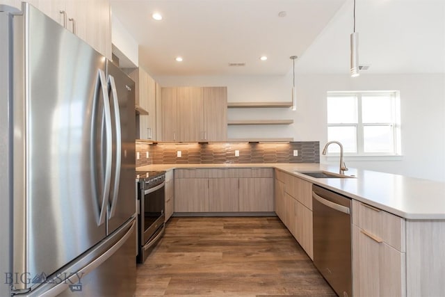 kitchen with sink, stainless steel appliances, tasteful backsplash, light brown cabinetry, and decorative light fixtures