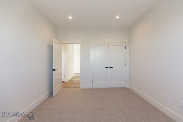 unfurnished bedroom featuring light carpet and a closet