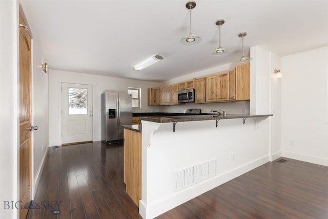 kitchen with a kitchen bar, appliances with stainless steel finishes, dark hardwood / wood-style flooring, kitchen peninsula, and hanging light fixtures