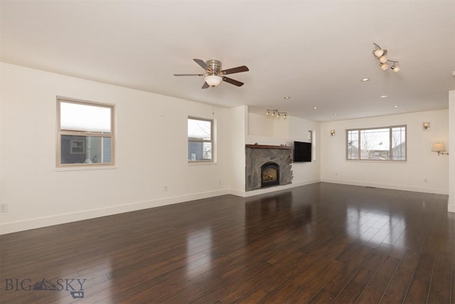 unfurnished living room featuring ceiling fan, a fireplace, and dark hardwood / wood-style floors