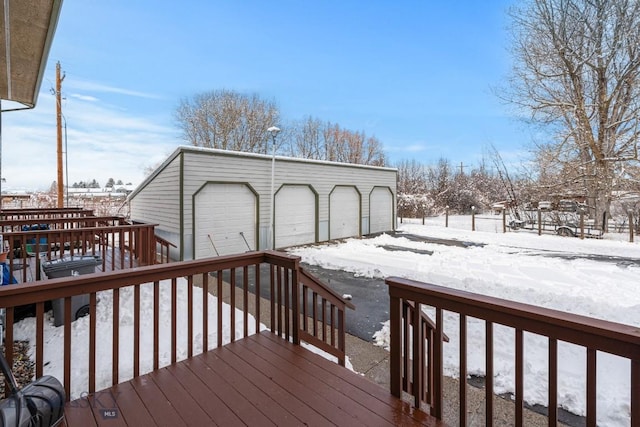 snow covered deck featuring an outdoor structure and a garage