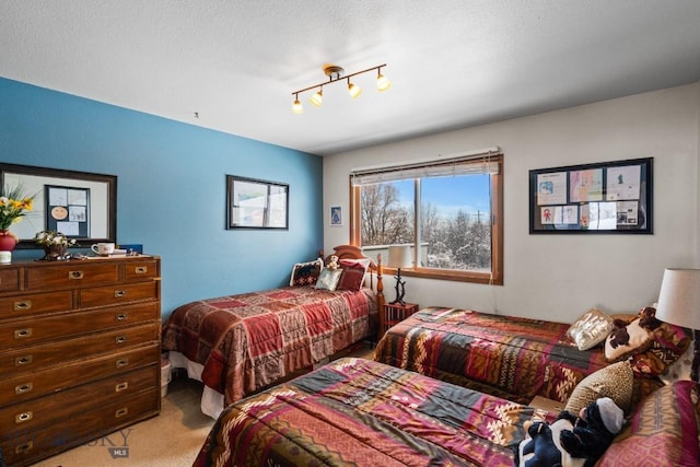 bedroom with carpet, a textured ceiling, and rail lighting