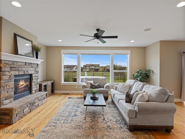 living room with a fireplace, ceiling fan, light hardwood / wood-style floors, and plenty of natural light