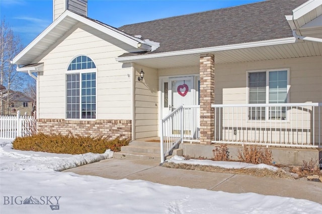 snow covered property entrance with covered porch