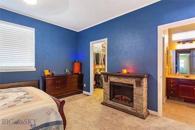 bedroom with a fireplace, a spacious closet, light carpet, connected bathroom, and a closet