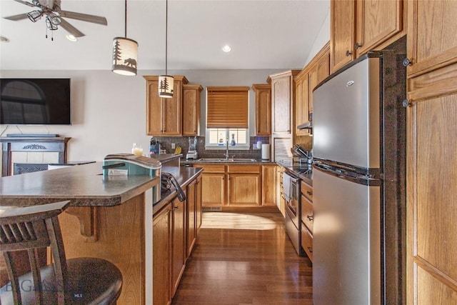 129 Red Mtn, Butte, MT 59701 - kitchen with stainless steel appliances, a sink, dark countertops, a kitchen breakfast bar, and dark wood-style floors