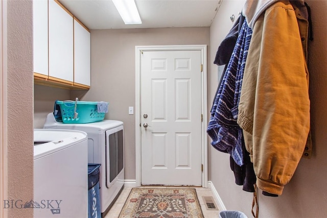 clothes washing area featuring light tile patterned floors, separate washer and dryer, and cabinets