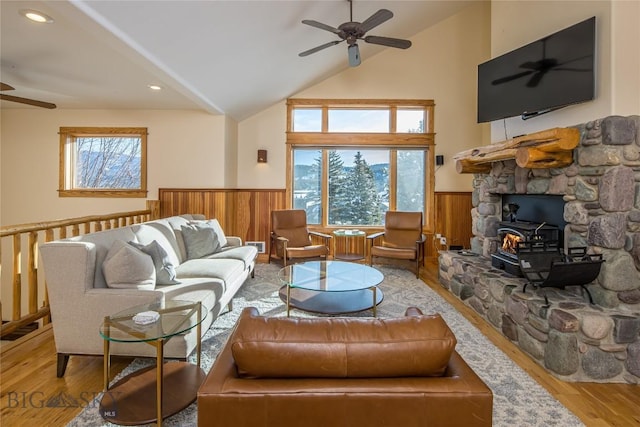 living room with light hardwood / wood-style floors, plenty of natural light, lofted ceiling, and a wood stove