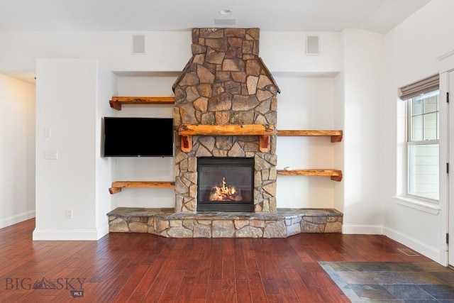 unfurnished living room featuring wood-type flooring, plenty of natural light, a fireplace, and built in shelves