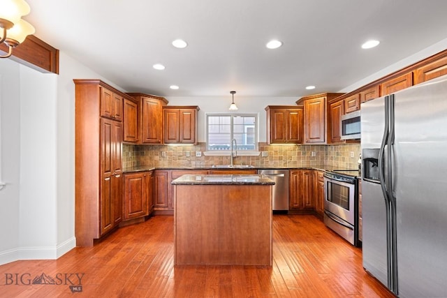 kitchen with appliances with stainless steel finishes, pendant lighting, sink, backsplash, and a center island