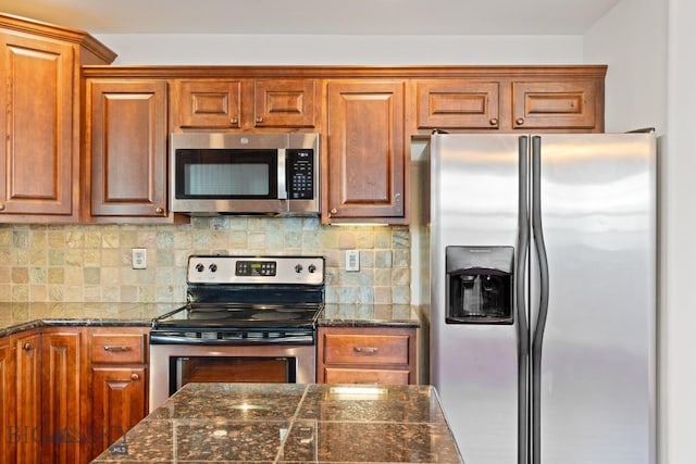 kitchen featuring stainless steel appliances, tasteful backsplash, and dark stone counters