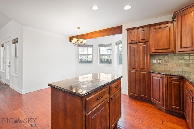 kitchen featuring tasteful backsplash, a kitchen island, dark wood-type flooring, and a chandelier