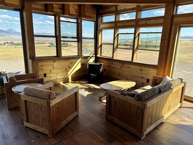 sunroom featuring a rural view, a mountain view, a wealth of natural light, and a wood stove