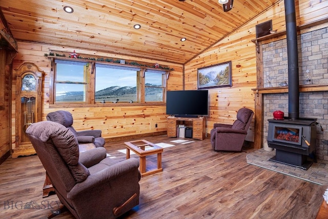 living room with wood ceiling, wood walls, a wood stove, and lofted ceiling