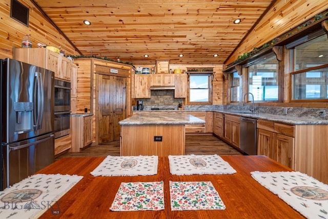 kitchen featuring vaulted ceiling, a kitchen island, dark hardwood / wood-style flooring, appliances with stainless steel finishes, and sink