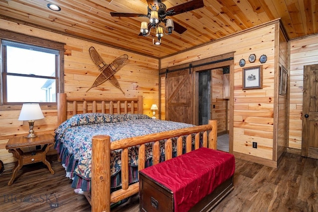 bedroom featuring wooden walls, wooden ceiling, ceiling fan, a barn door, and dark hardwood / wood-style floors