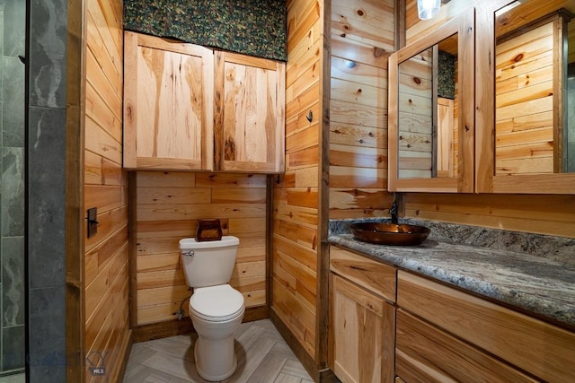 bathroom featuring toilet, wooden walls, parquet flooring, and vanity