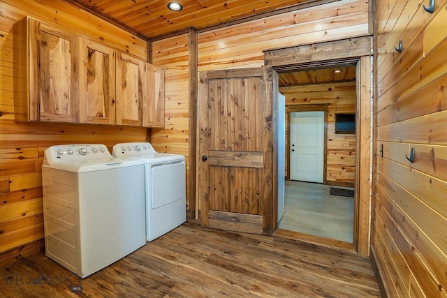 washroom with cabinets, wooden ceiling, washing machine and dryer, dark wood-type flooring, and wooden walls