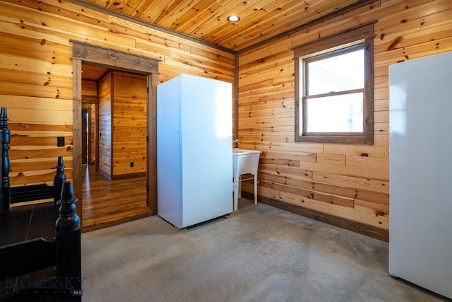 interior space featuring concrete floors, wooden ceiling, and wood walls