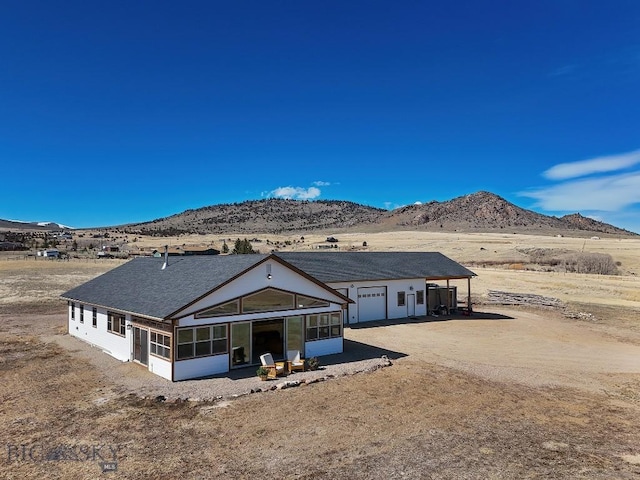 rear view of property featuring a sunroom, a garage, and a mountain view